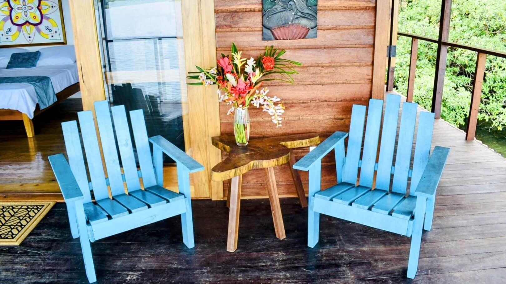 Two blue chairs and a table with flowers on top of it.