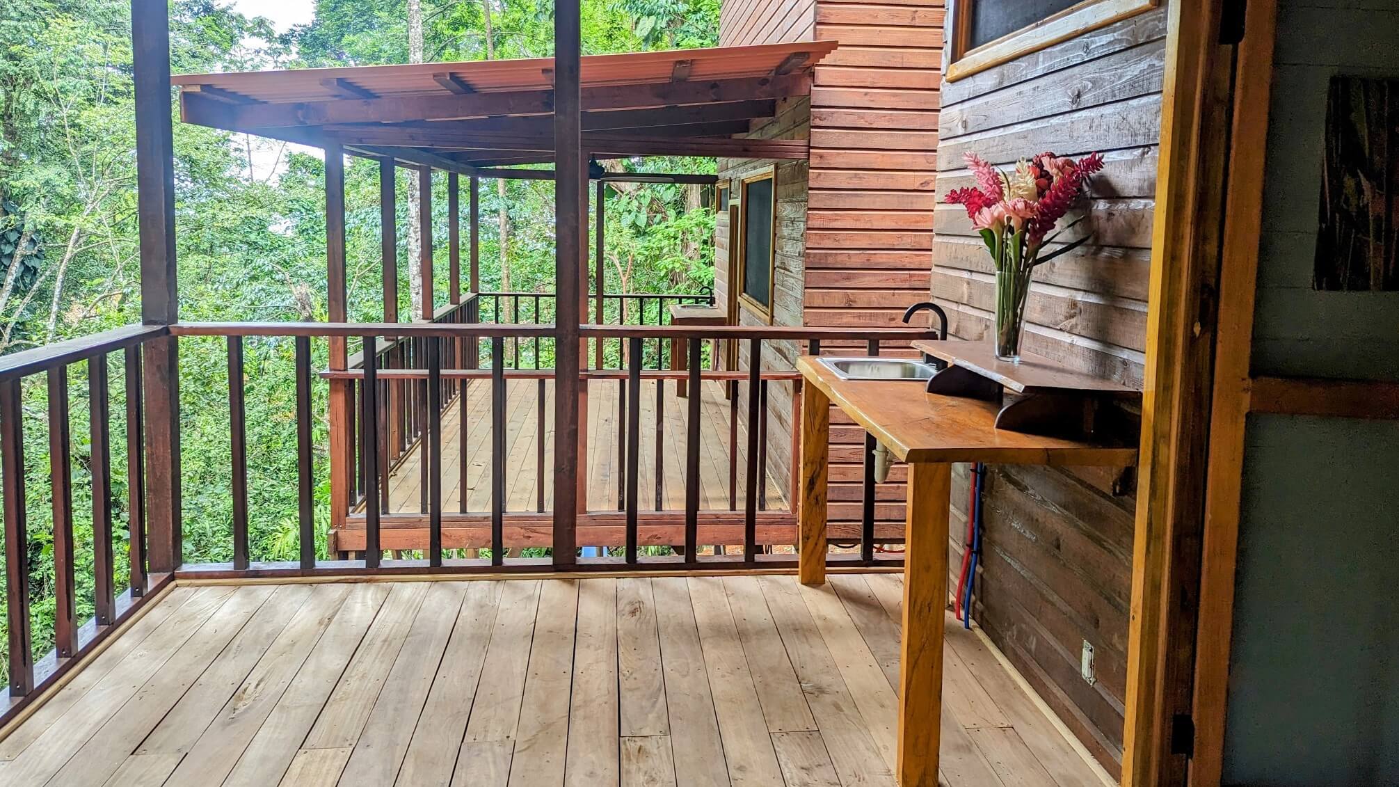 A wooden table and bench on the porch of a house.