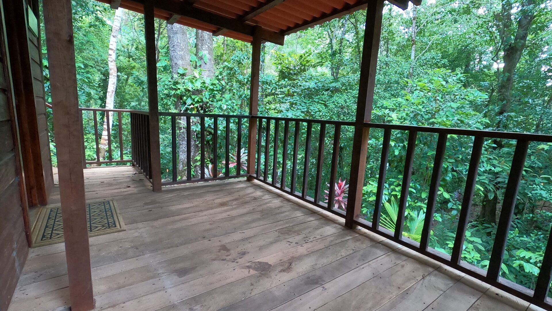 A wooden deck with a railing and a view of trees.