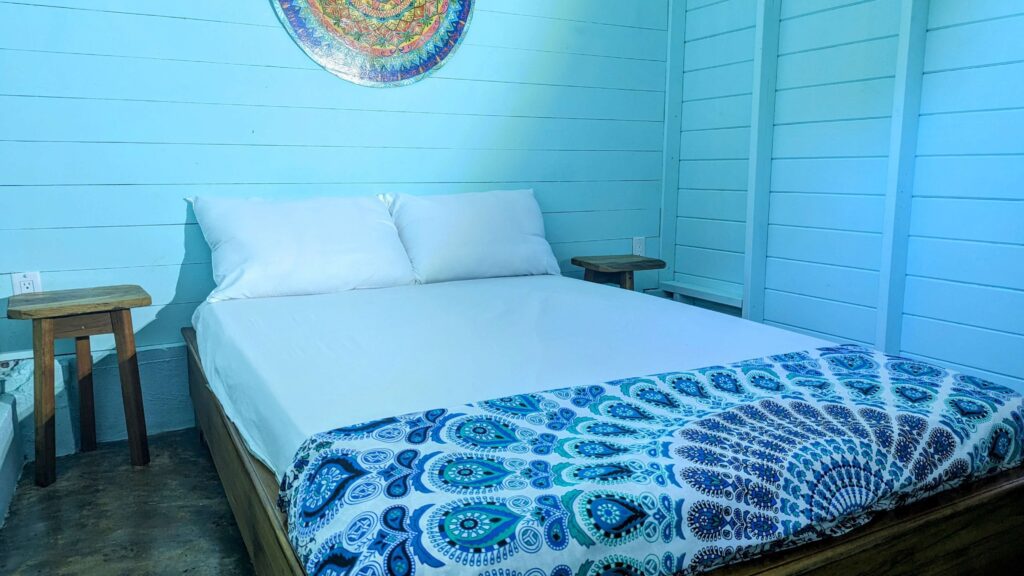 A bed room with a blue wall and white wooden headboard